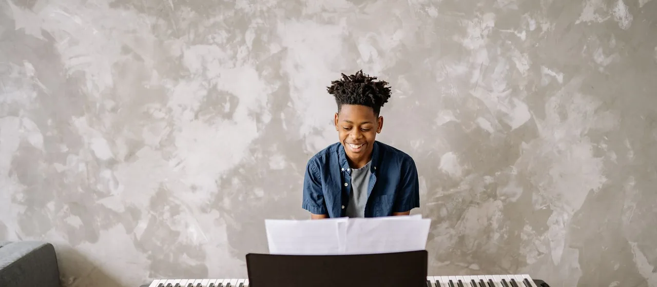 Criança sorrindo enquanto toca um teclado em casa